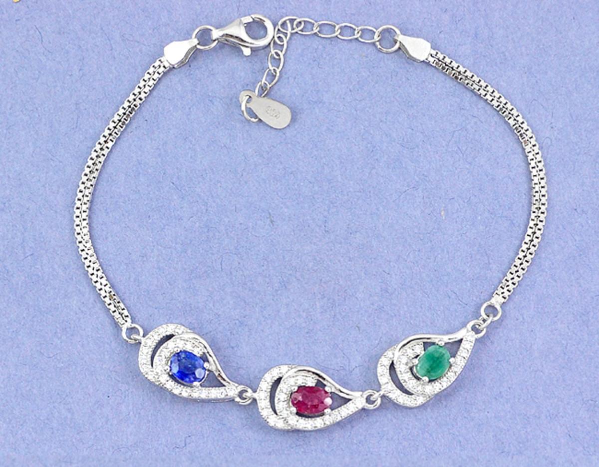 A 925 silver bracelet set with oval cut emerald, ruby and sapphire surrounded by white stones, L.