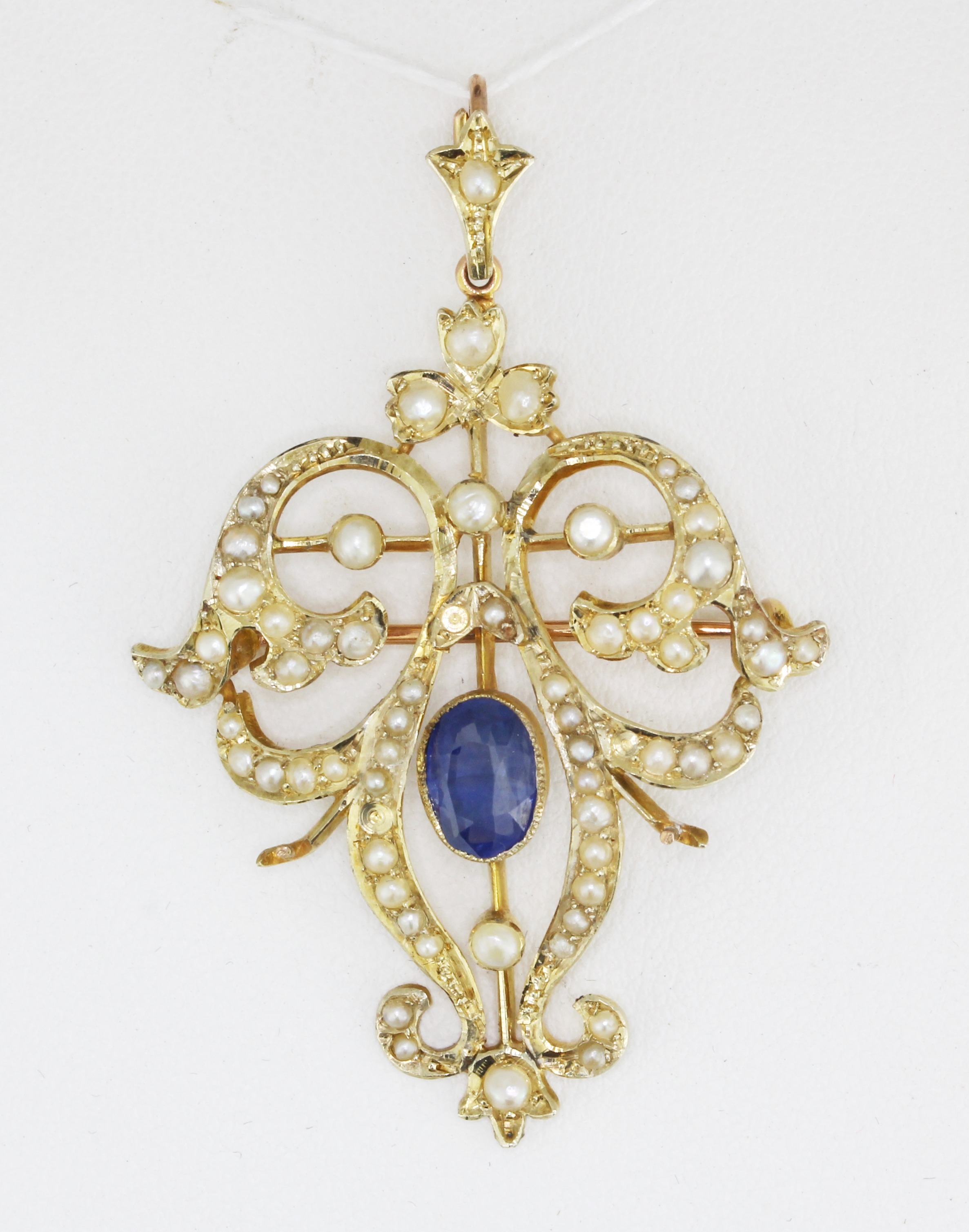 An Edwardian 9ct yellow gold (stamped 9ct) brooch / pendant set with an oval cut sapphire and