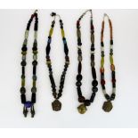 Four Tibetan tribal necklaces of mixed old bronze and glass beads, longest 72cm.