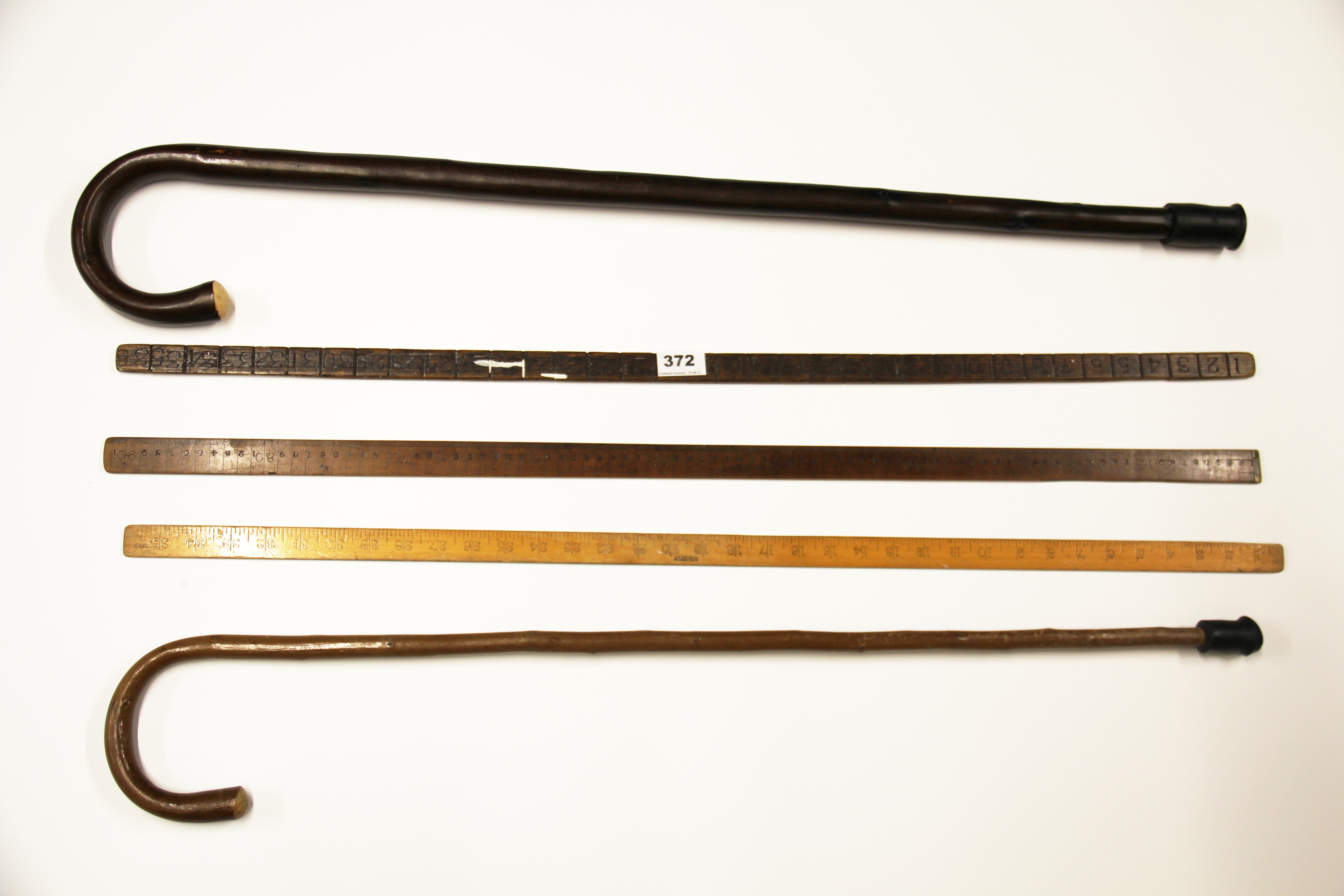 Three early wooden yard sticks and two walking sticks.