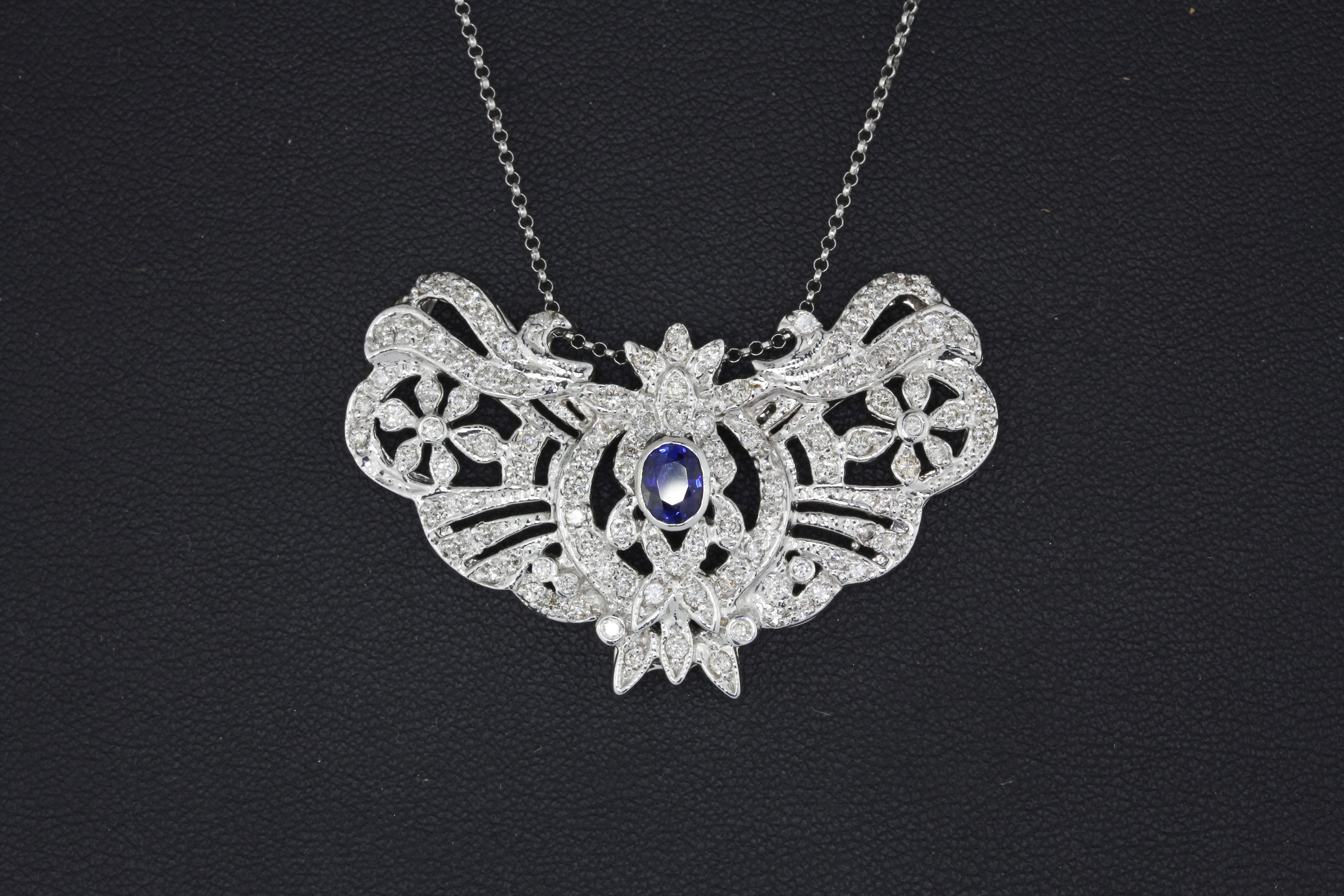 A white metal (tested high carat gold) necklace set with an oval cut sapphire and brilliant cut