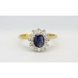 An 18ct yellow gold cluster ring set with an oval cut sapphire and diamonds, (K.5).
