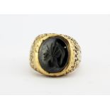 A gentleman's 9ct yellow gold (worn hallmark) and carved haemetite centurion signet ring, (P).