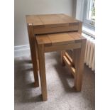 A contemporary nest of two solid oak side tables, largest 45 x 45 x 60cm.