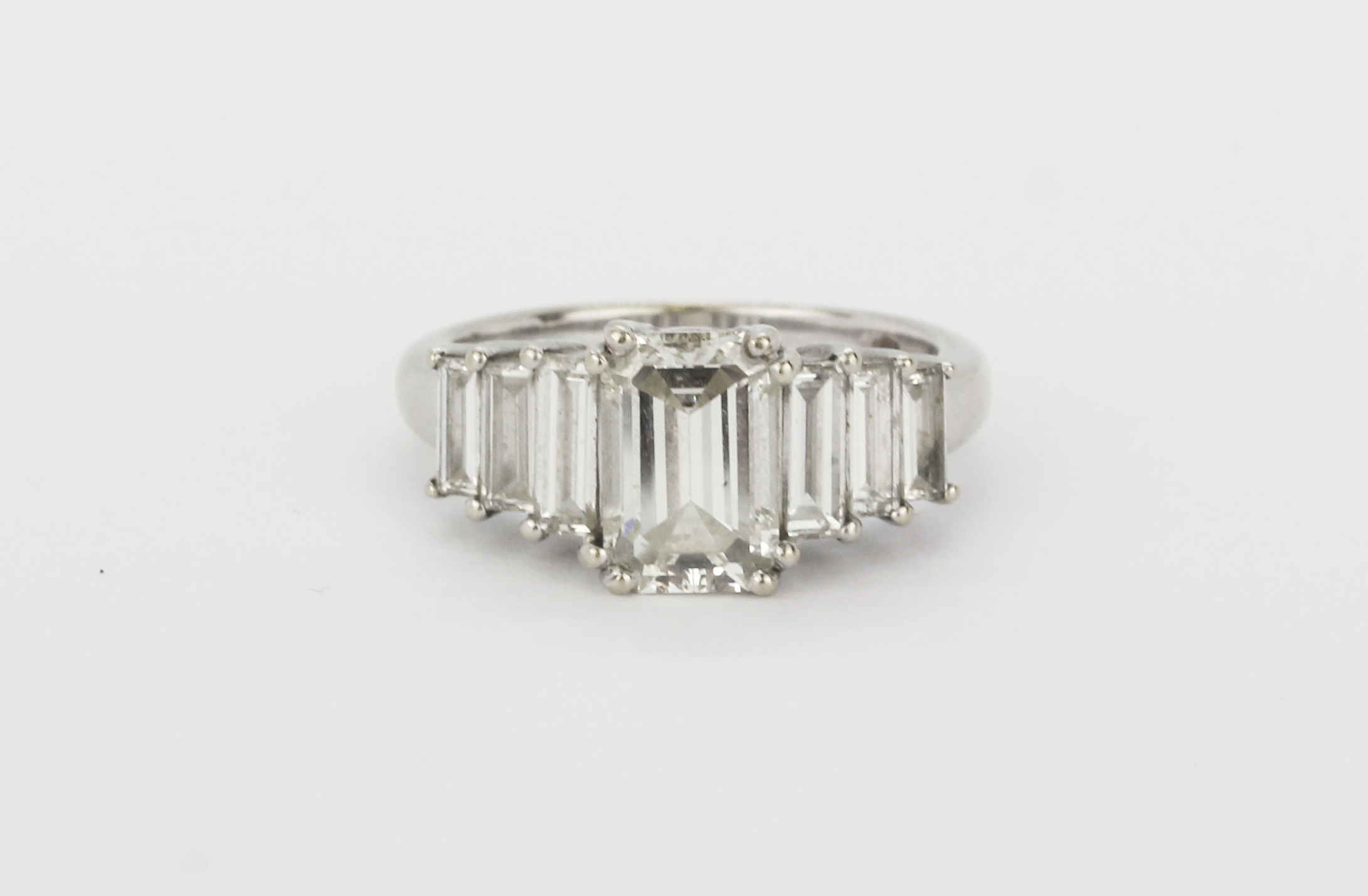 A hallmarked 18ct white gold ring set with a centre emerald cut diamond (approx 2ct) with further