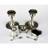 A three piece hallmarked cruet set together with a pair of hallmarked silver candlesticks.
