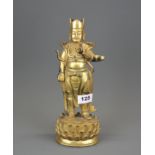 A Tibetan gilt bronze figure of a standing guardian deity, H. 28cm.