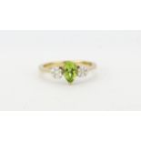 A hallmarked 9ct yellow gold ring set with a pear cut peridot and brilliant cut diamond cluster