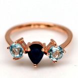 A 925 silver rose gold gilt ring set with a pear cut sapphire flanked by blue topaz, (S).