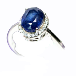 A 925 silver cluster ring set with an oval cut sapphire surrounded by white stones, (S).