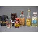 A bakelite cased Watermans ink bottle with a travelling measuring cup and three vintage bottles.