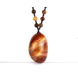 A lovely polished banded agate pebble, L. 5.5cm. On a silk and banded agate bead necklace.