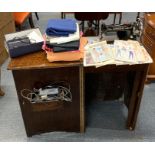 A singer sewing machine in an Art Deco oak cabinet, with accessories and dressmaking patterns.