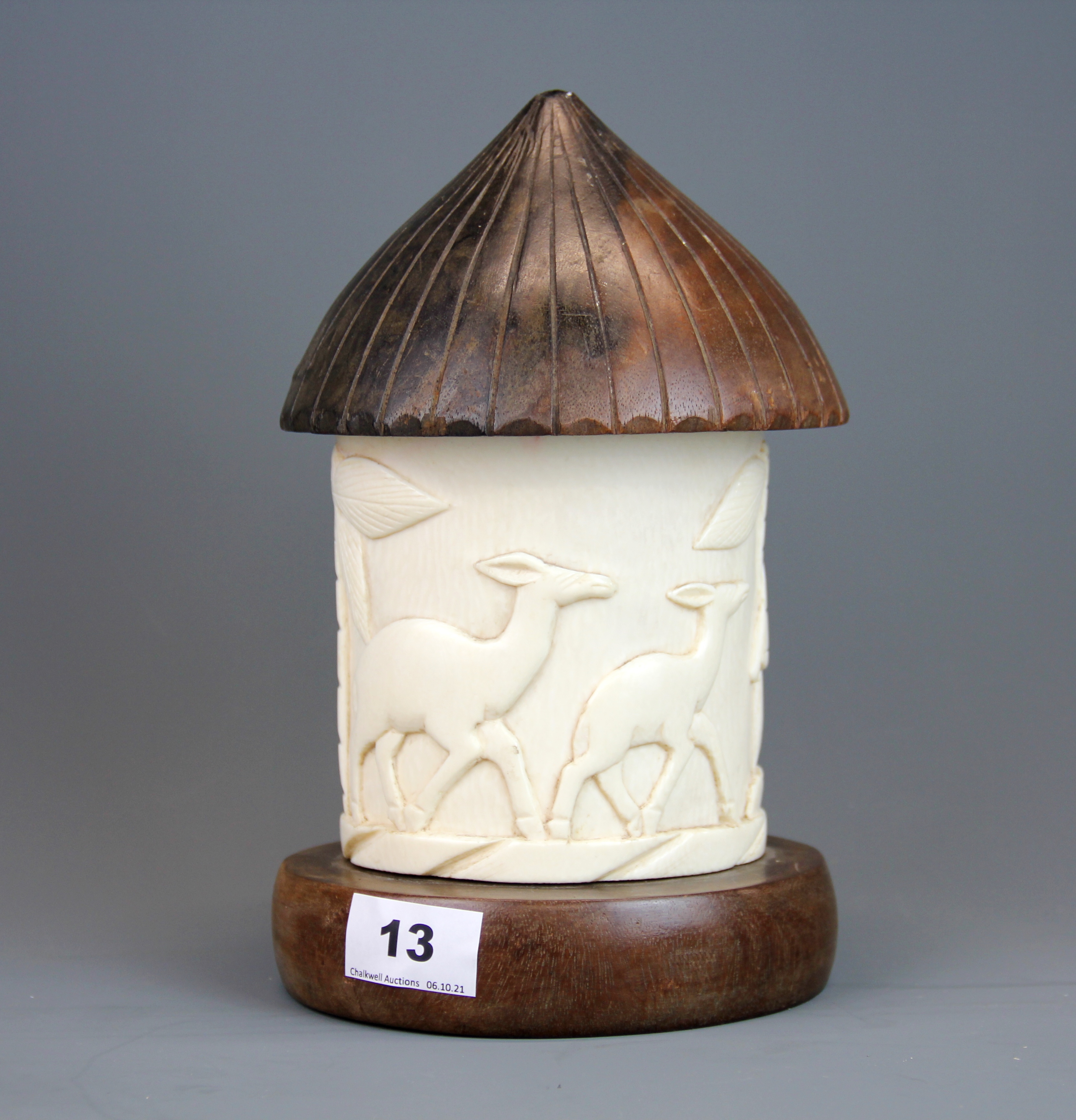 An early 20th Century African carved ivory and hardwood box in the shape of a tribal hut, H. 23cm.