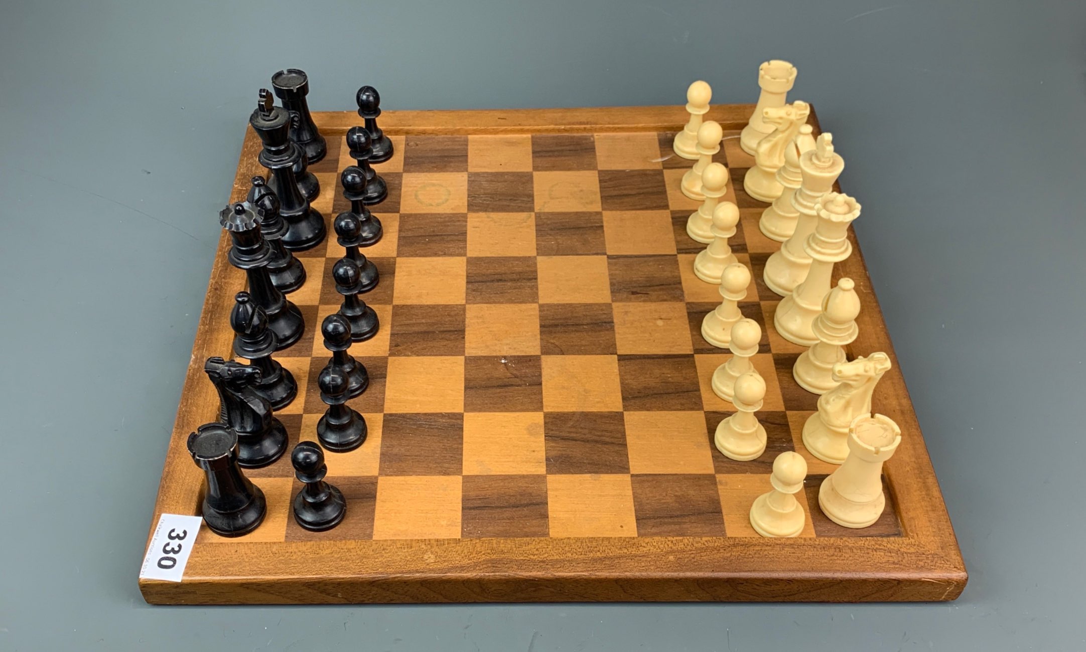 A vintage celluloid chess set with wooden board, king H. 9.5cm.