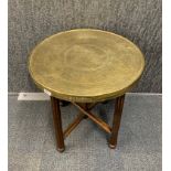 An Eastern brass topped folding table, Dia. 59.5cm.