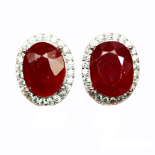 A pair of 925 silver earrings set with an oval cut ruby surrounded by white stones, L. 1.5cm.