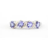 A hallmarked 9ct white gold ring set with oval cut tanzanites and diamonds, (N.5).