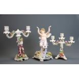 A German porcelain figure of a Cherub (repair to base) together with two candle holders.