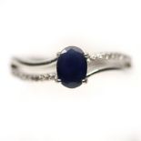 A 925 silver ring set with an oval cut sapphire and white stone set shoulders, (P.5).