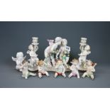A group of continental porcelain cherub figures, tallest 17cm. Candlesticks restored.