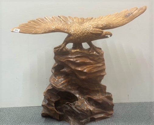 A large carved wooden figure of an eagle on a rock, H. 60cm. Wing span 78cm.
