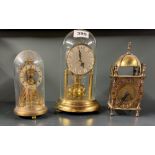 A brass lantern clock and two torsion pendulum clocks, tallest 22cm.