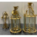 Three gilt brass porch lanterns, largest 64cm.