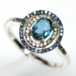 A 925 silver cluster ring set with London blue topaz, sapphires and white stones, (S).