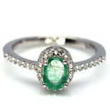 A 925 silver cluster ring set with oval cut emeralds and white stones, (O).