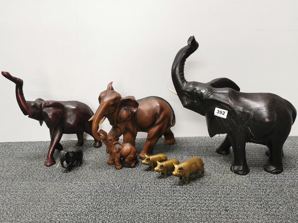 Two carved wooden elephant figures with a resin figure and a group of brass pigs, tallest H. 39cm.