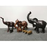 Two carved wooden elephant figures with a resin figure and a group of brass pigs, tallest H. 39cm.