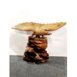 A large carved wooden figure of an eagle on a rock, H. 60cm. Wing span 78cm.