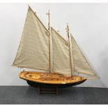 A superb large handmade wooden model of a two masted yacht, H. 117cm, L. 117cm, with stand.