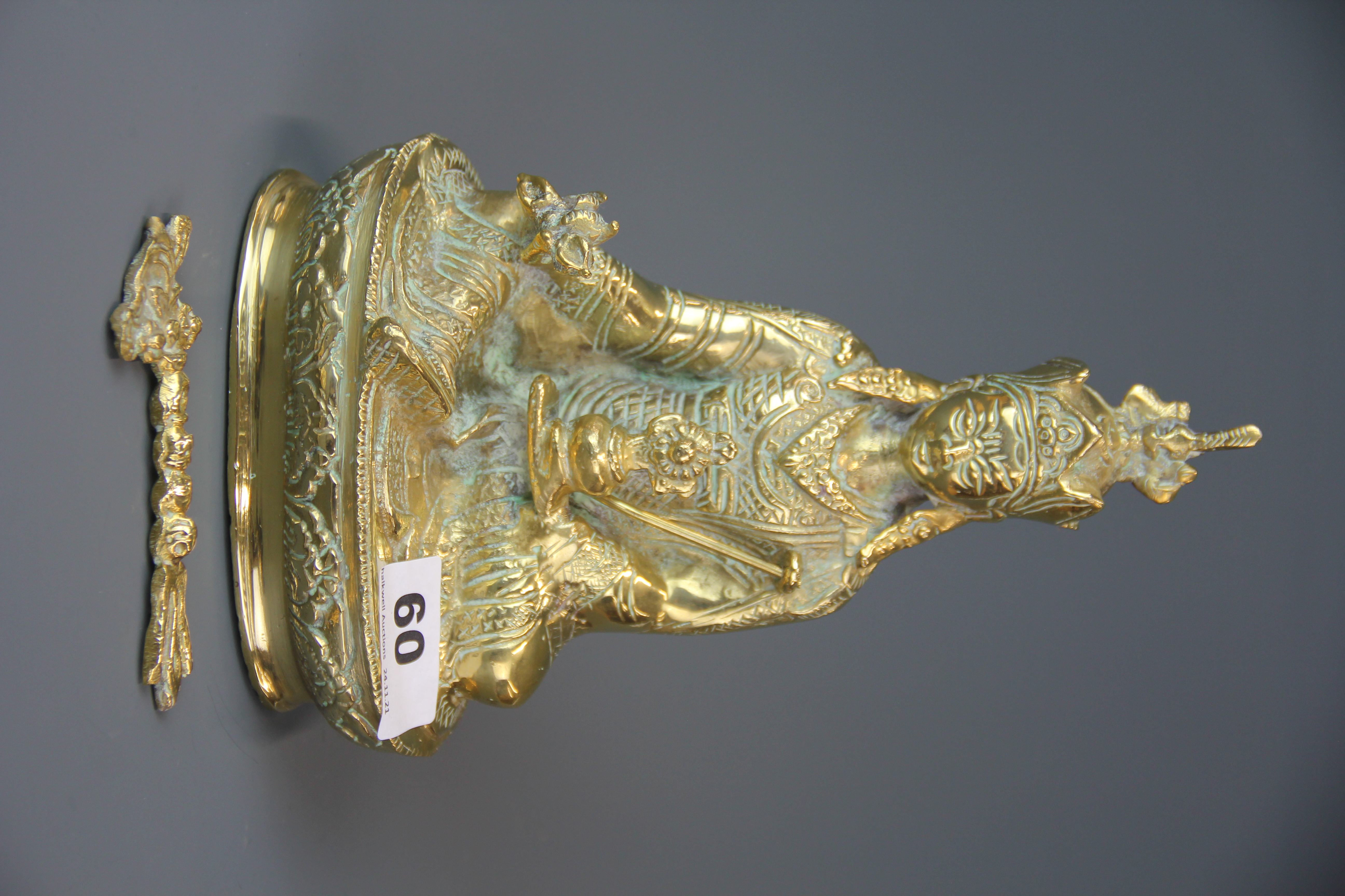 A mid 20th century Tibetan bronze/brass figure of a seated deity, H. 22cm. (A/F to staff).