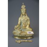 A mid 20th century Tibetan bronze/brass figure of a seated deity, H. 22cm. (A/F to staff).