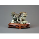 A finely carved Chinese mixed colour jade figure of a lion dog playing with a ribbon and ball