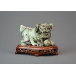 A finely carved Chinese mixed colour jade figure of a lion dog playing with a ribbon and ball
