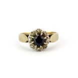 A hallmarked 9ct yellow gold cluster ring set with a round cut sapphire surrounded by diamonds, (M.