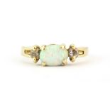 A 14ct yellow gold (stamped 14k) ring set with a cabochon oval cut opal and stone set shoulders, (