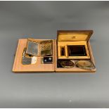 A group of vintage compacts and lighters in a London Fire Brigade box.