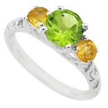 A 925 silver ring set with a round cut peridot flanked by citrines, (P.5).