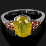 A 925 silver ring set with an oval cut yellow sapphire and spessartine garnet set shoulders, (P.5).