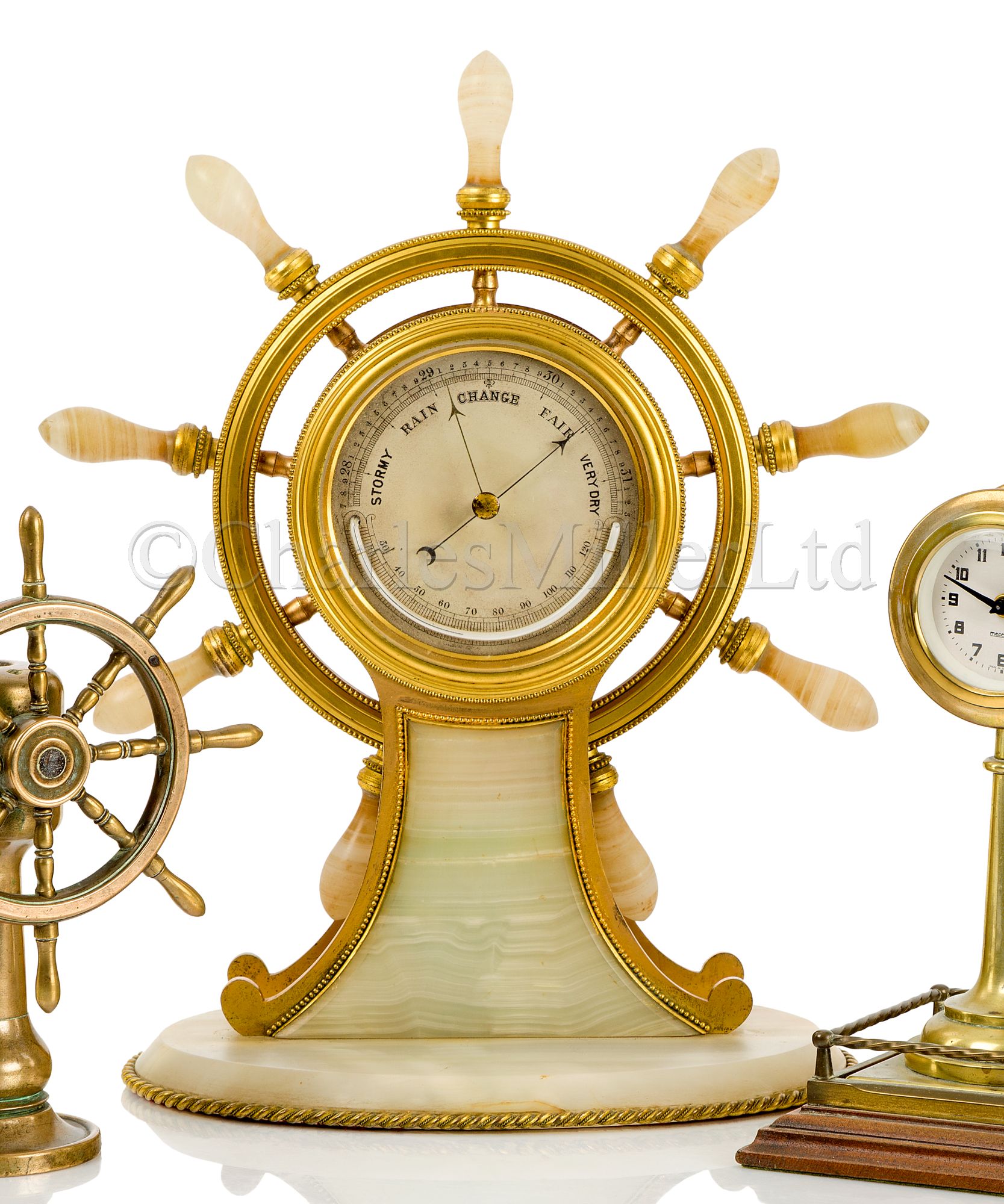 A FINE AND LARGE GILT, BRASS AND AGATE SHIP’S WHEEL DESK BAROMETER, ATTRIBUTED TO BETJEMANN & SONS