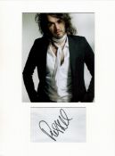 Russell Brand signature piece mounted below colour photo. Approx size 16x12.Good condition. All