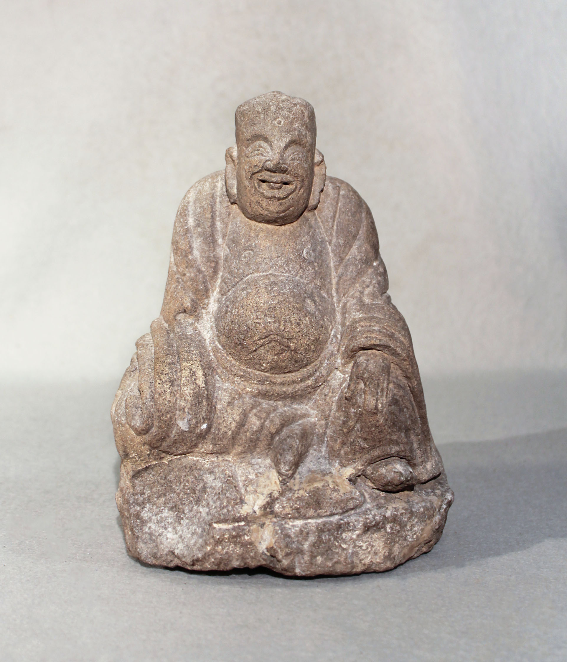 A Chinese cream stone seated figure of a smiling Putai, perhaps late Ming Dynasty, 21cm high