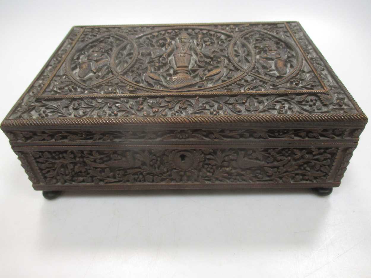 An Indian/Asian carved wood box, probably c.1900, with three figures to the lid, on brass feet, 23 x