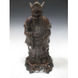A carved wood figure of a Chinese immortal, standing holding a staff, on a stand, 30cm high inc.