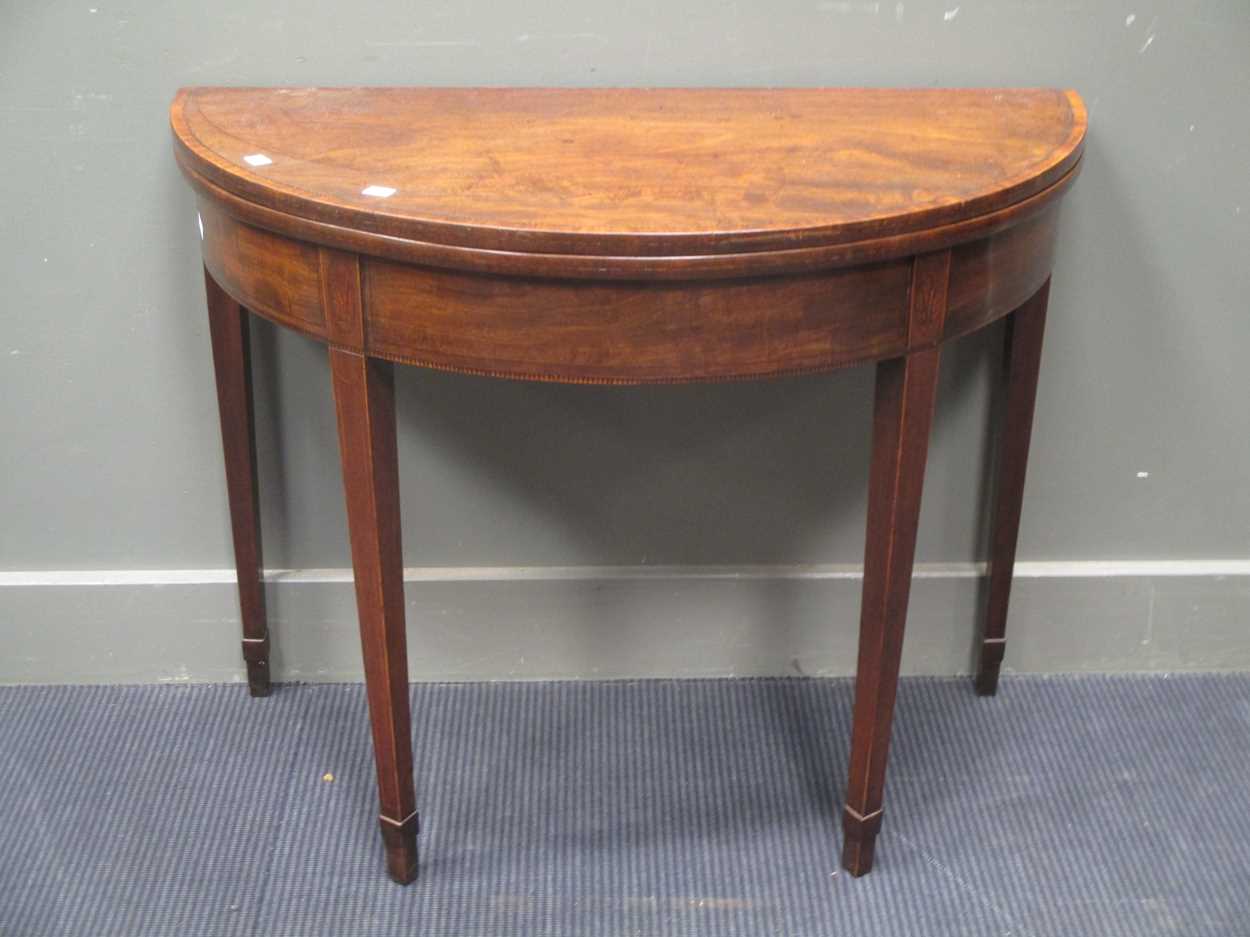 A George III mahogany demi-lune card table, with chevron banded top, on square tapering legs with