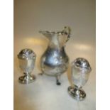 A pair of silver pepperettes and a cream jug embossed with a farm scene (3)